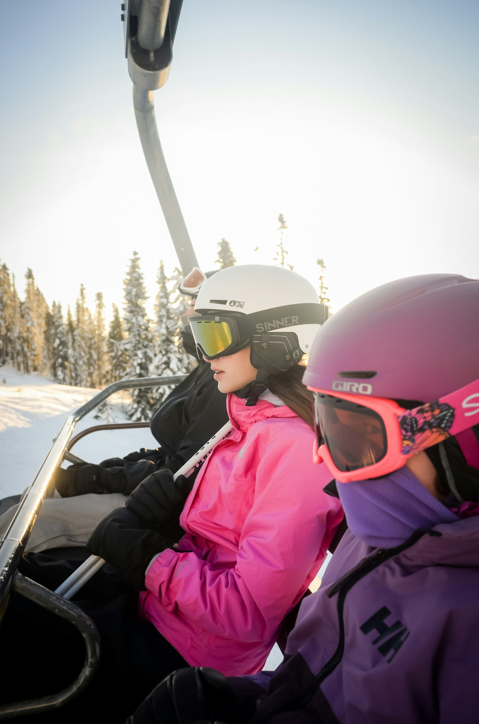 Two skiers riding a chairlift in sunshine